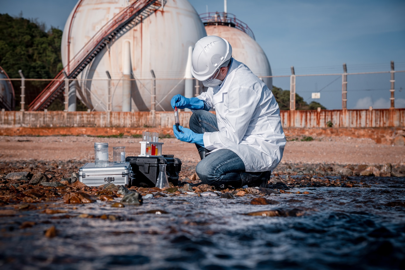 Un scientifique portant un uniforme et des gants de sécurité dans le cadre de l’analyse de l’eau de travail et de la qualité de l’eau en testant les eaux usées.